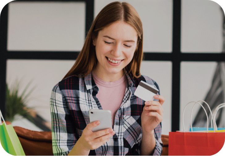 Young woman using a smartphone and credit card to order a FreeSIMCards online next to colorful shopping bags.